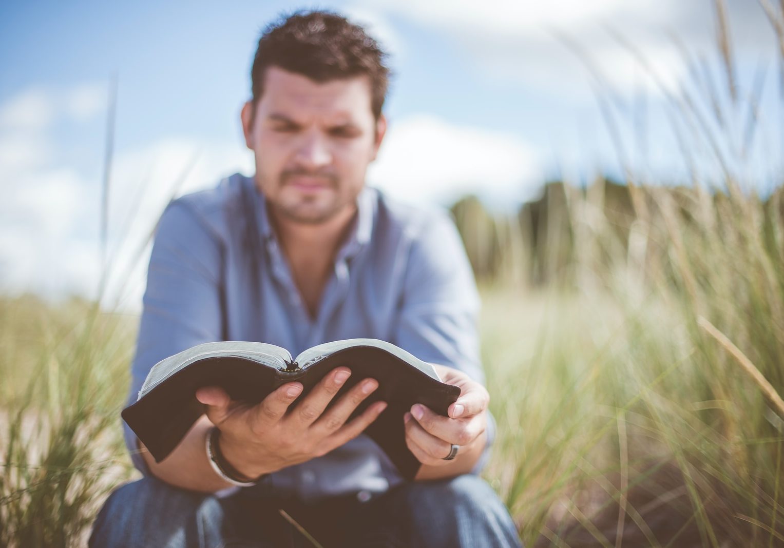 Photo by Ben White man reading book in grass field